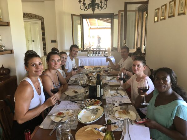 A group of people tasting wine and food at a table at Monti Cecubi winery